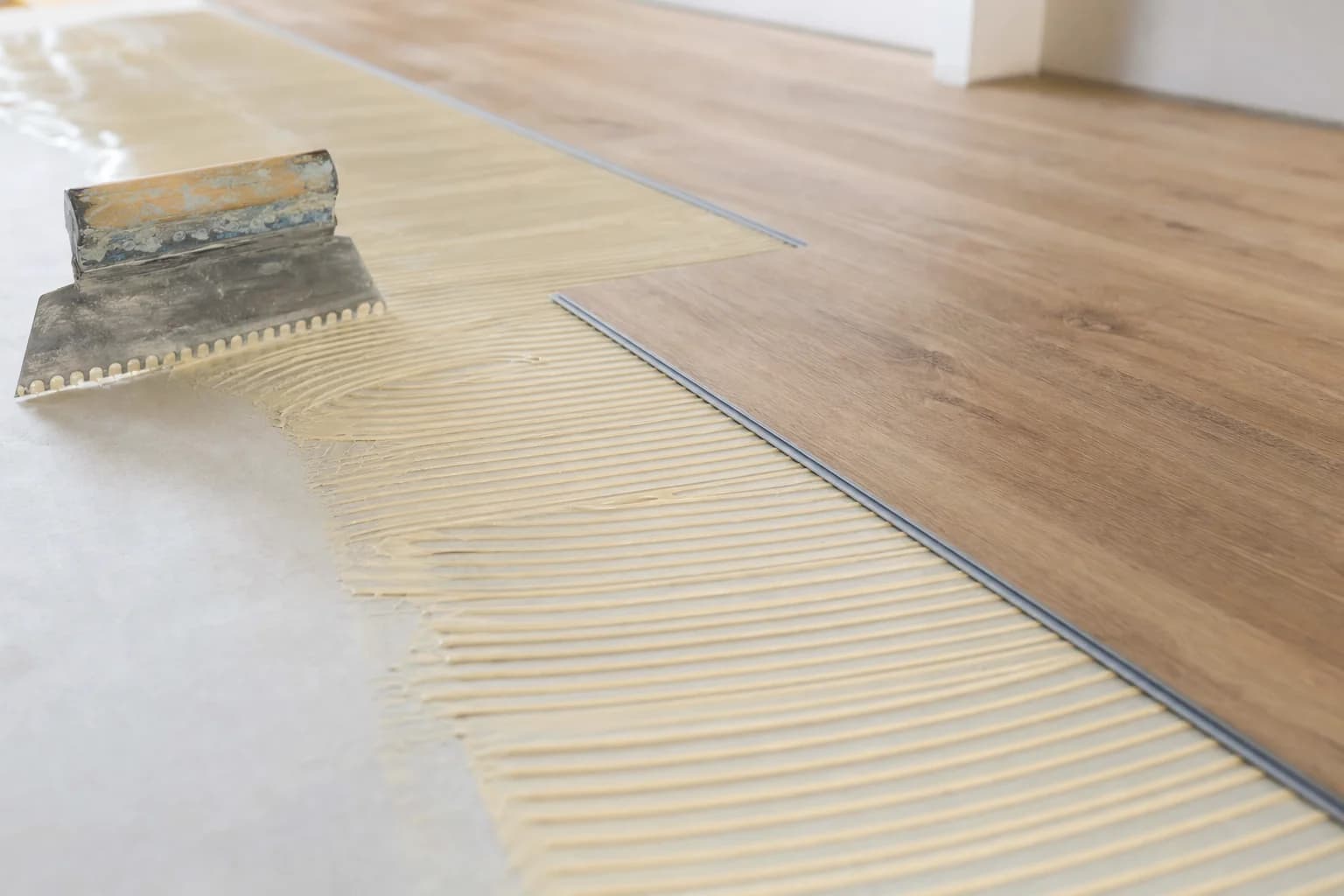 Glue down vinyl plank being laid into hard set adhesive over a prepared subfloor